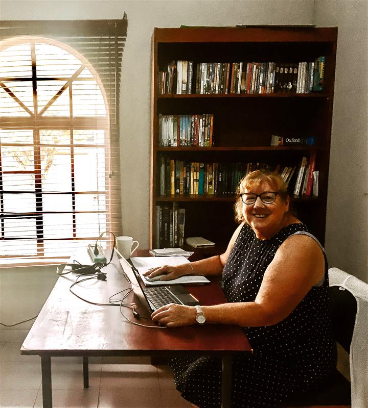 Jeanette working at her computer and smiling.