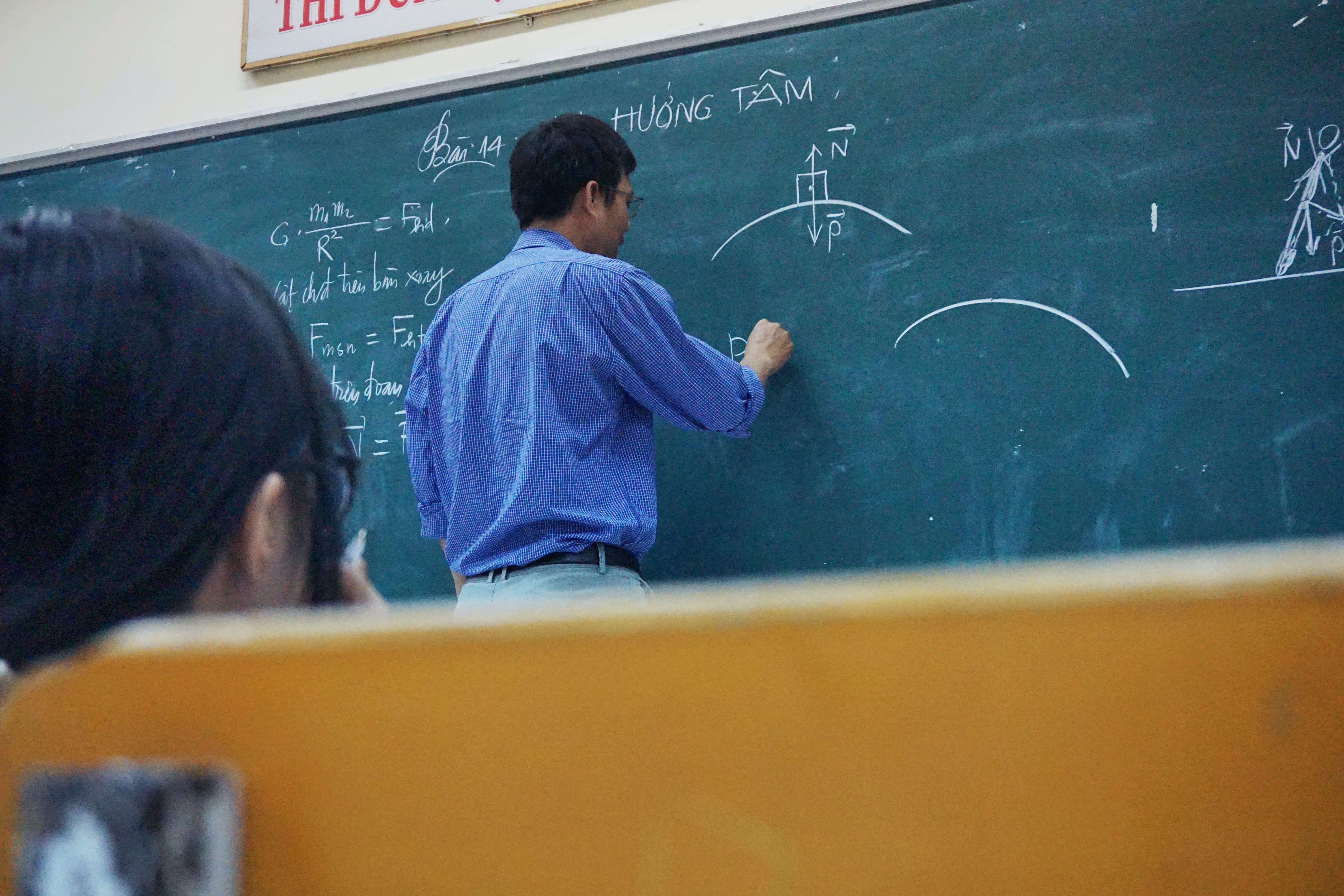Photo of a teacher writing on a chalkboard by Tra Nguyen on Unsplash.