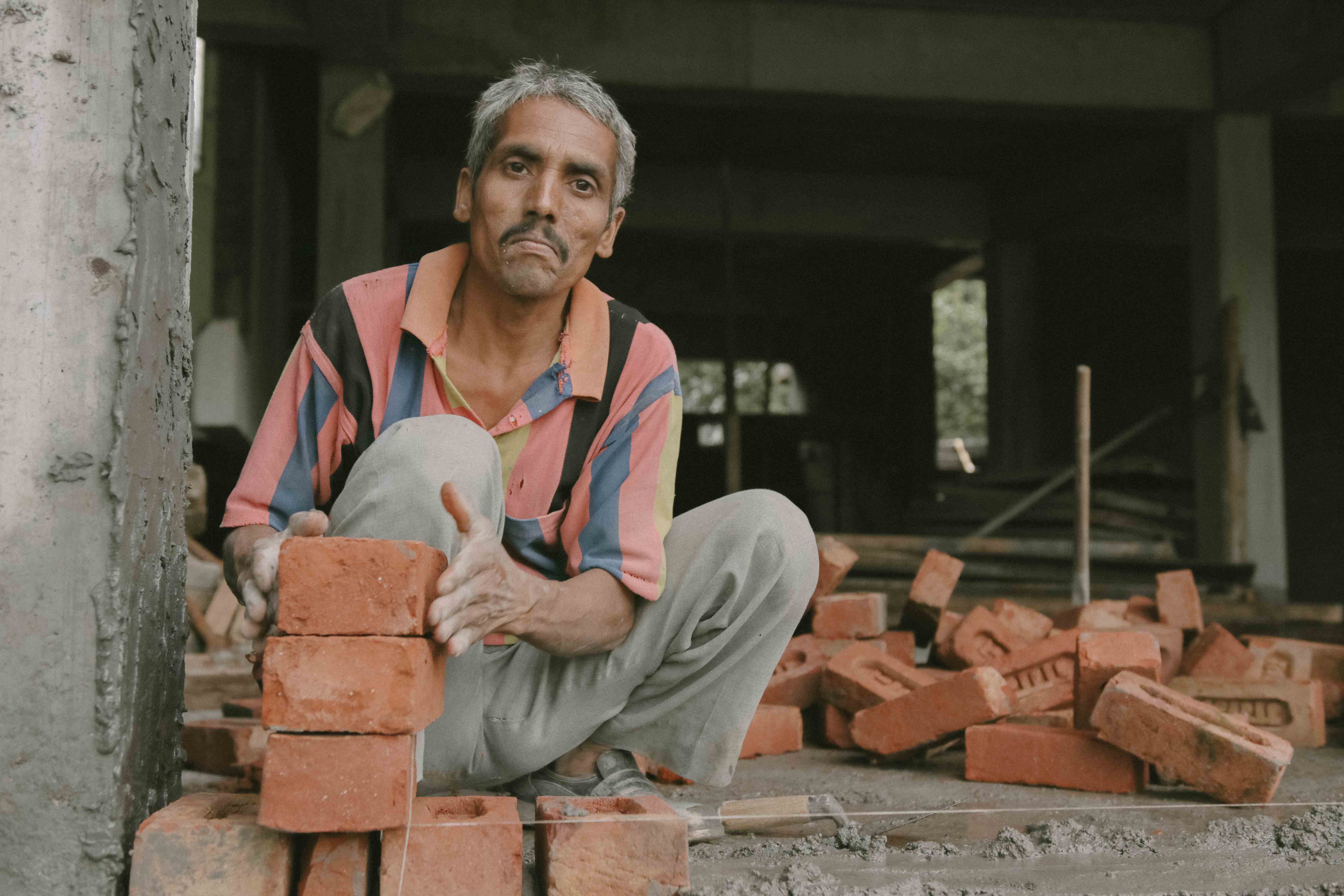 Photo of a man with a stack of bricks in front of him from India.