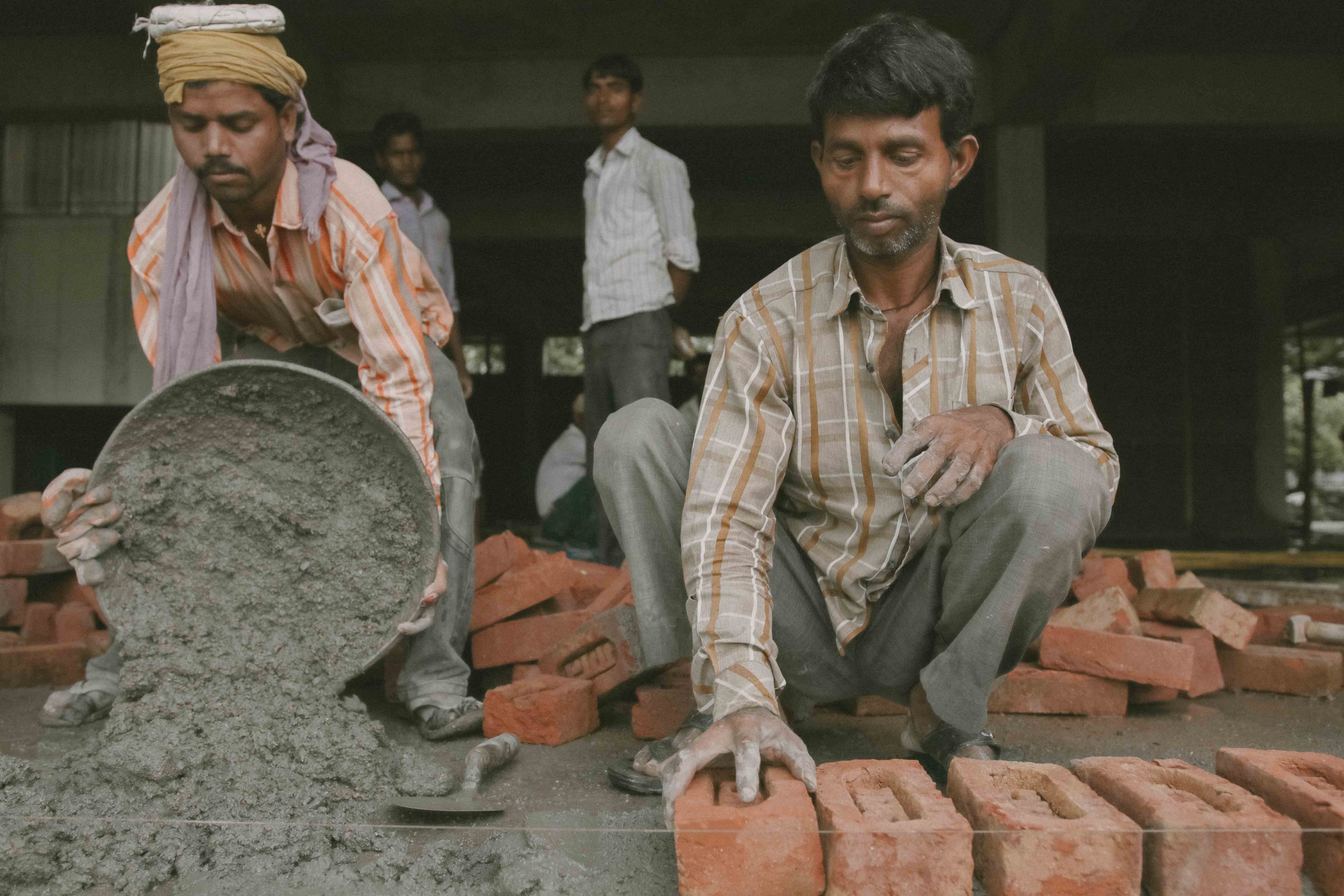 Photo of two men working on brick work from India.
