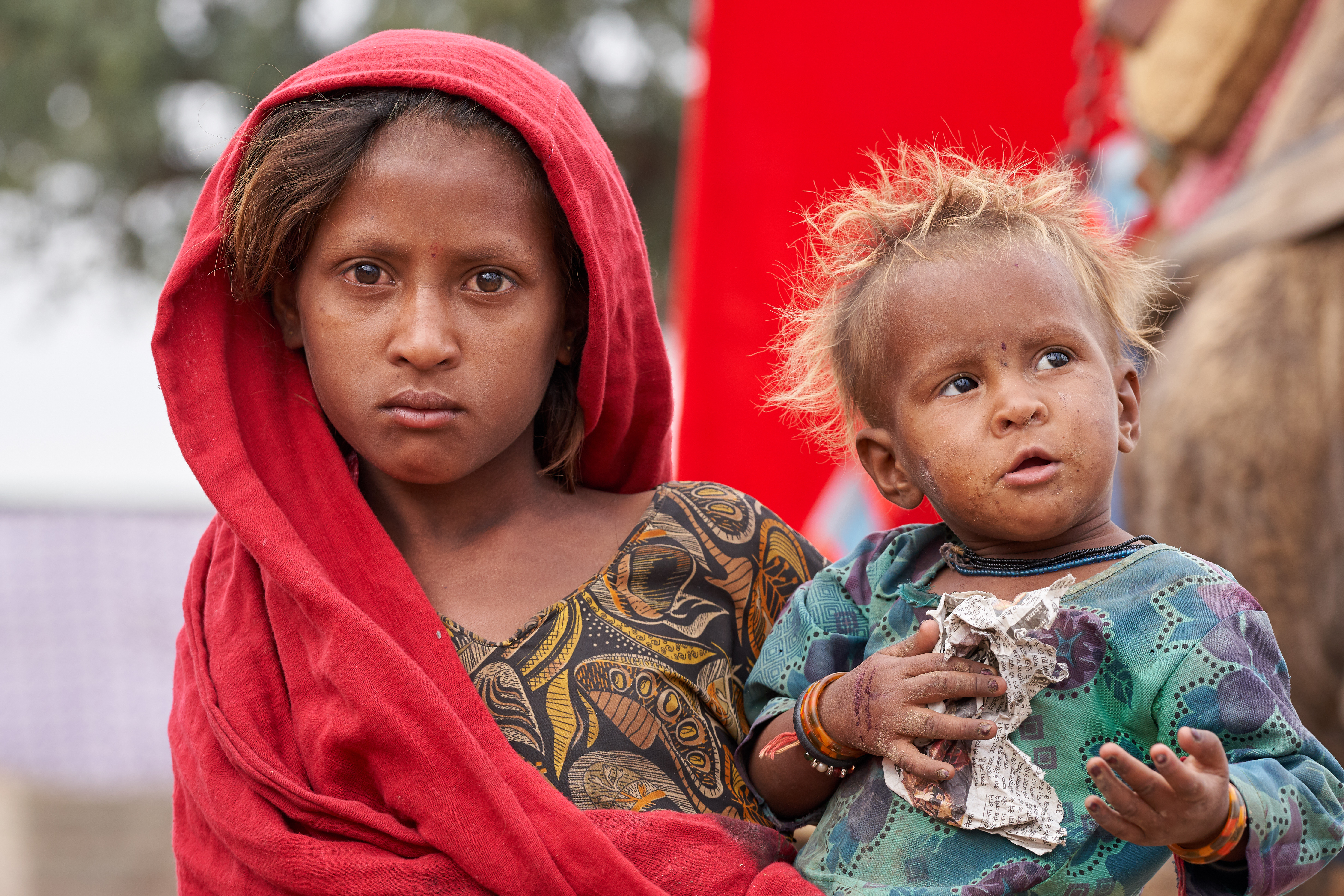 Photo of a girl wearing red holding a baby from Shutterstock.