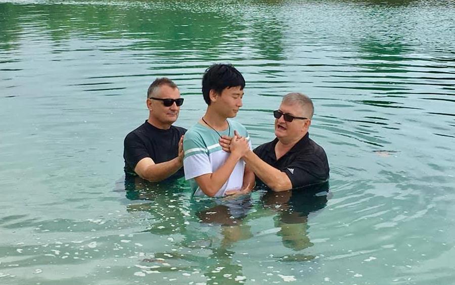 Dave Wood and colleague baptizing a youth in the lake.