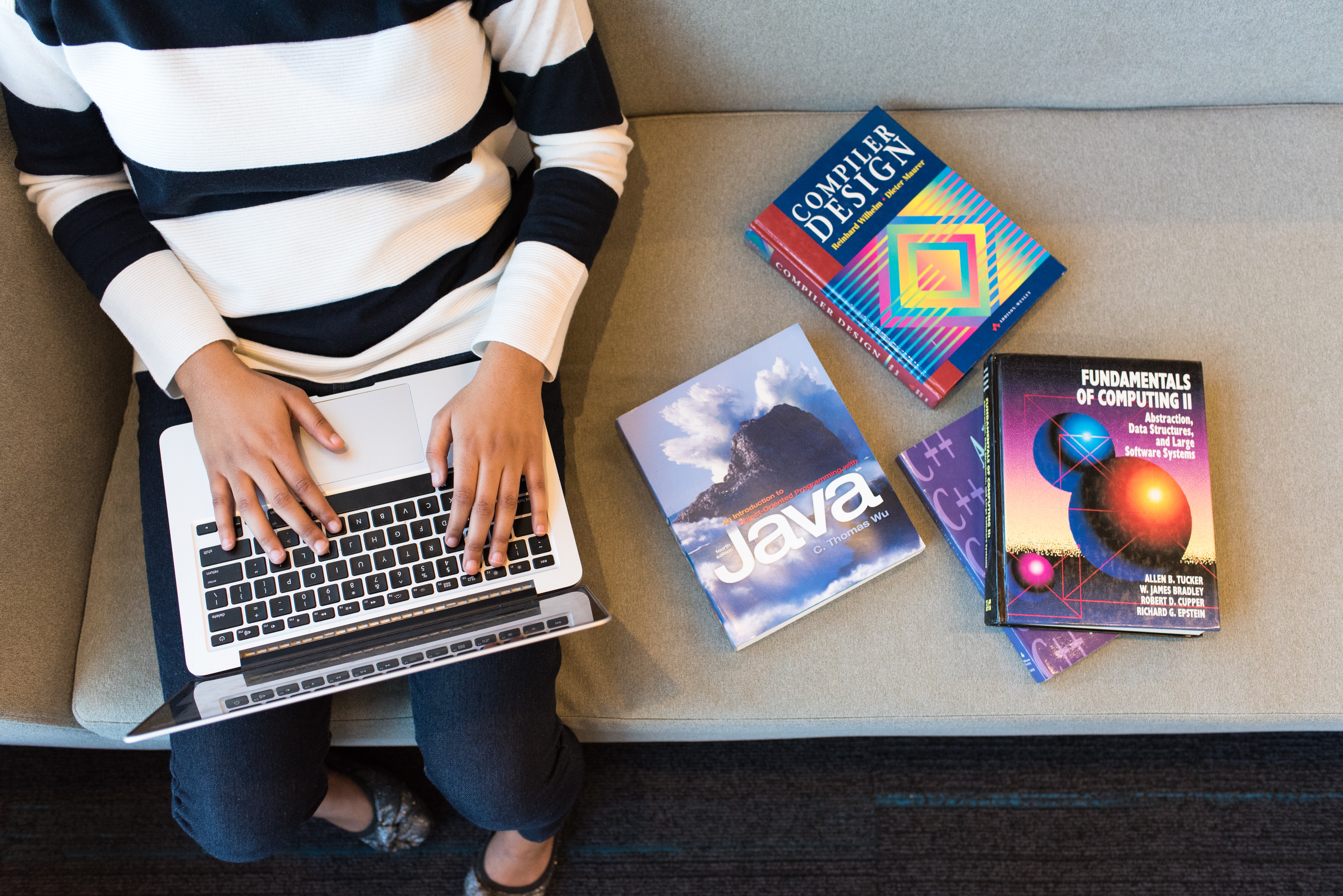 Photo of someone working on a laptop with programming books beside them by Christina Wocintechchat on Unsplash