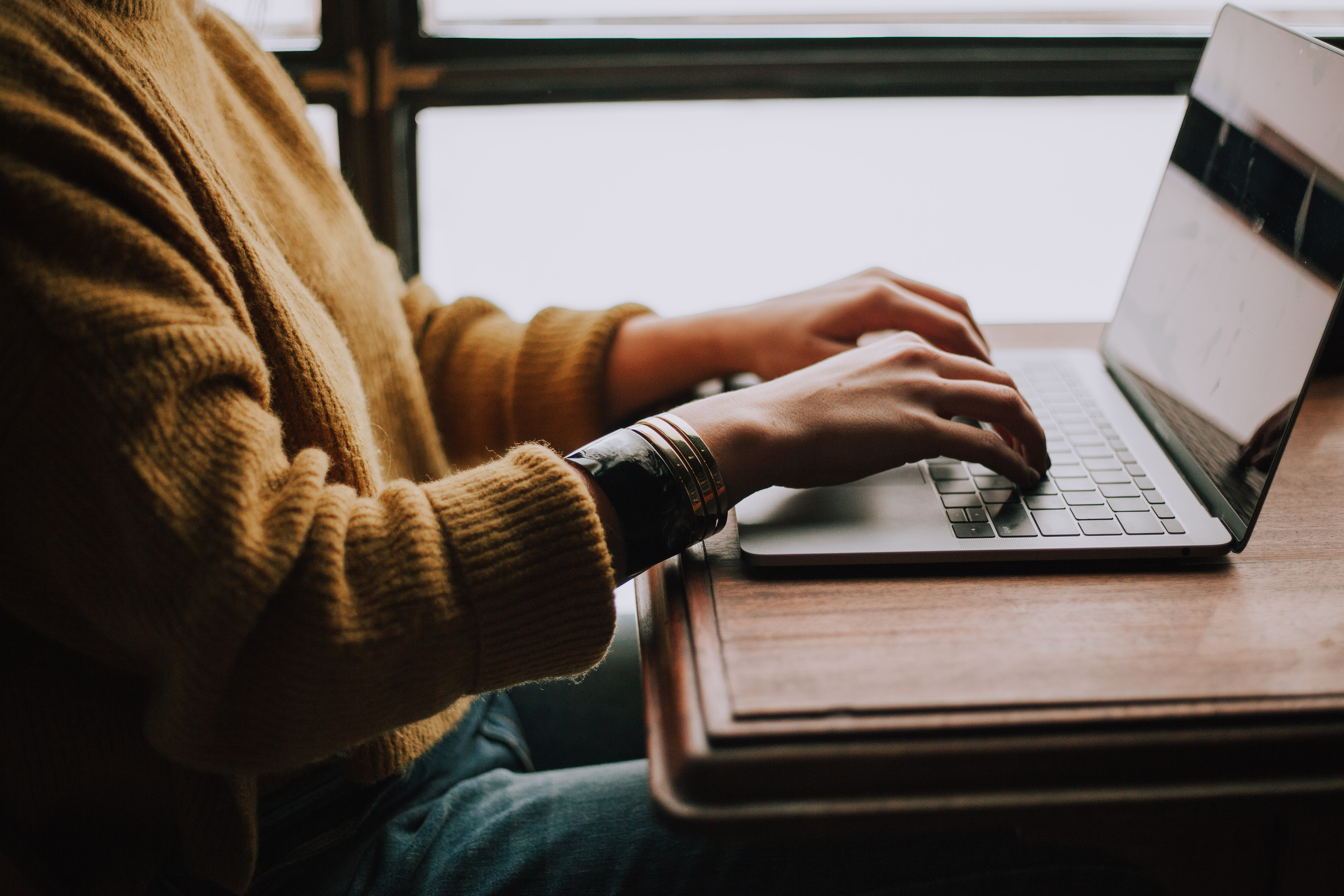 Photo by Christin Hume on Unsplash of a person sitting in front of a laptop.