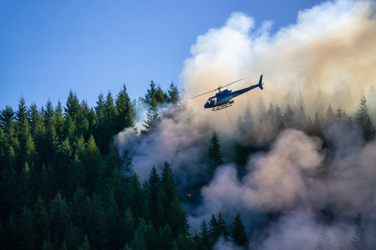 A helicopter flying over a wildfire.