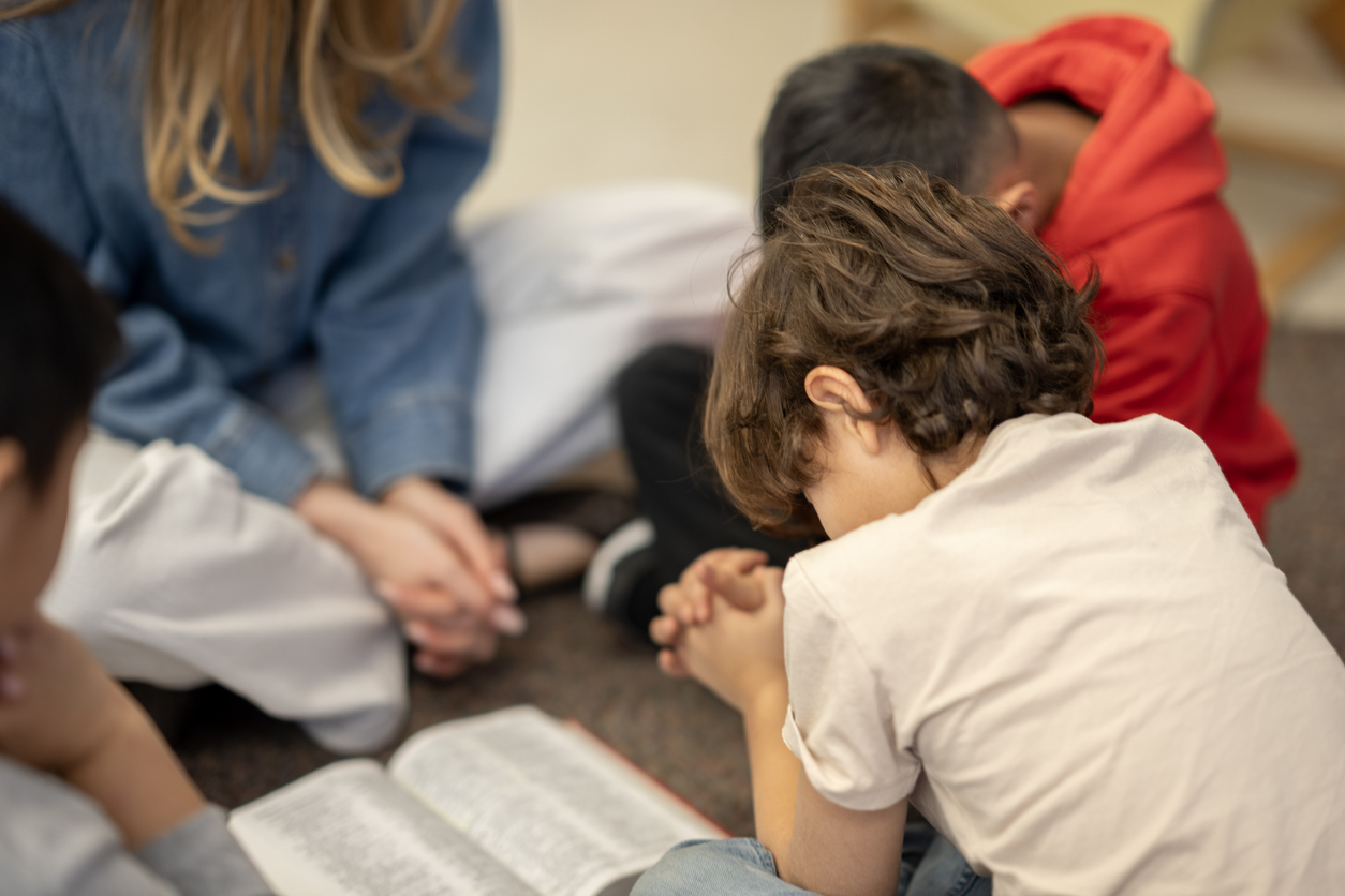A photo of children praying over a Bible.