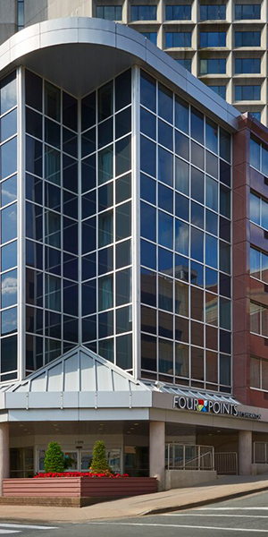 Four Points Halifax hotel exterior large glass building with planter full of red flowers out front