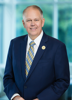Dr. William M Wilson in a blue suit with a yellow and blue striped tie